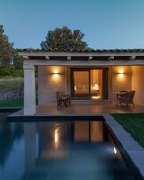 Un patio moderno al aire libre con piscina, dos sillas y una mesa.