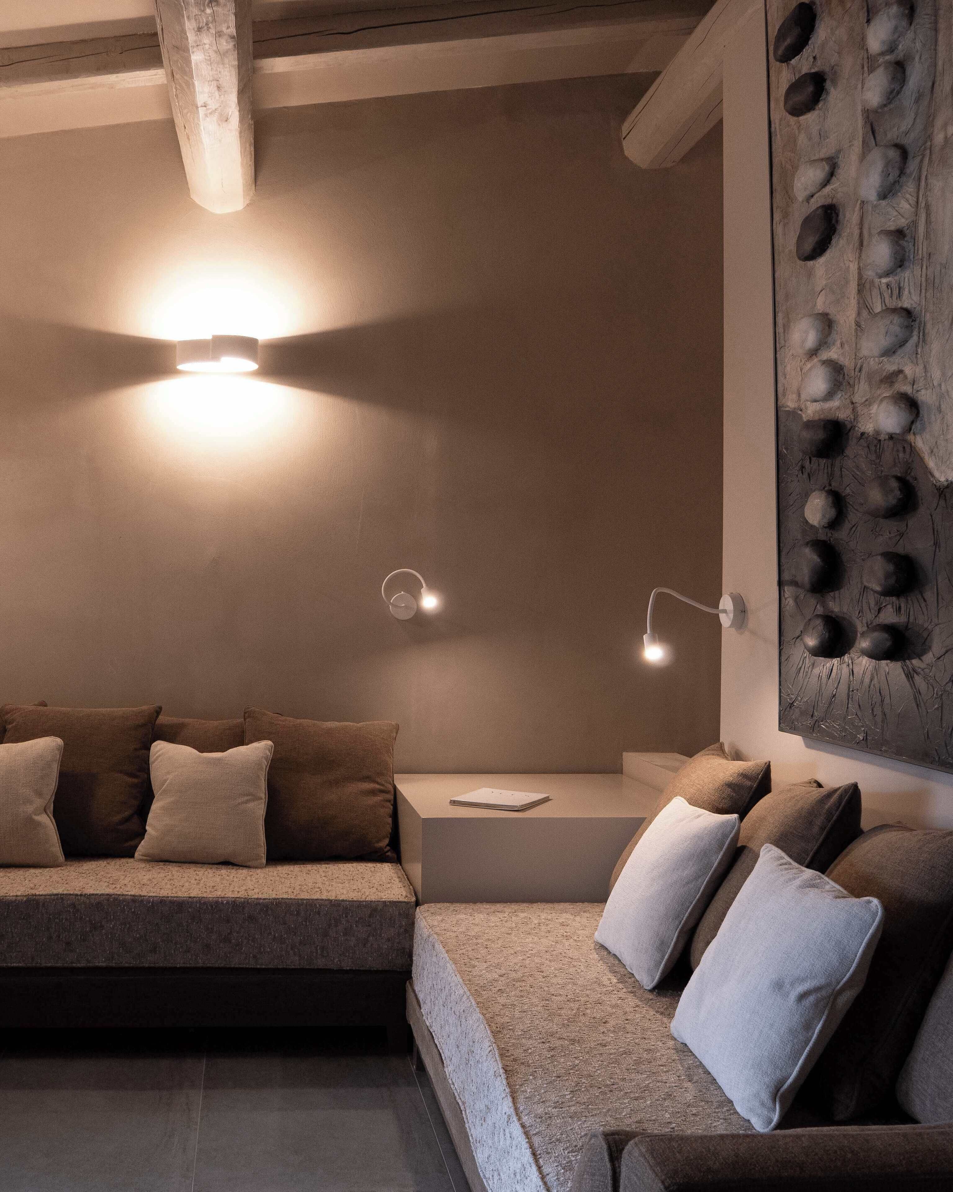 Una sala de estar moderna con un sofá seccional, una mesita auxiliar y un aplique de pared.