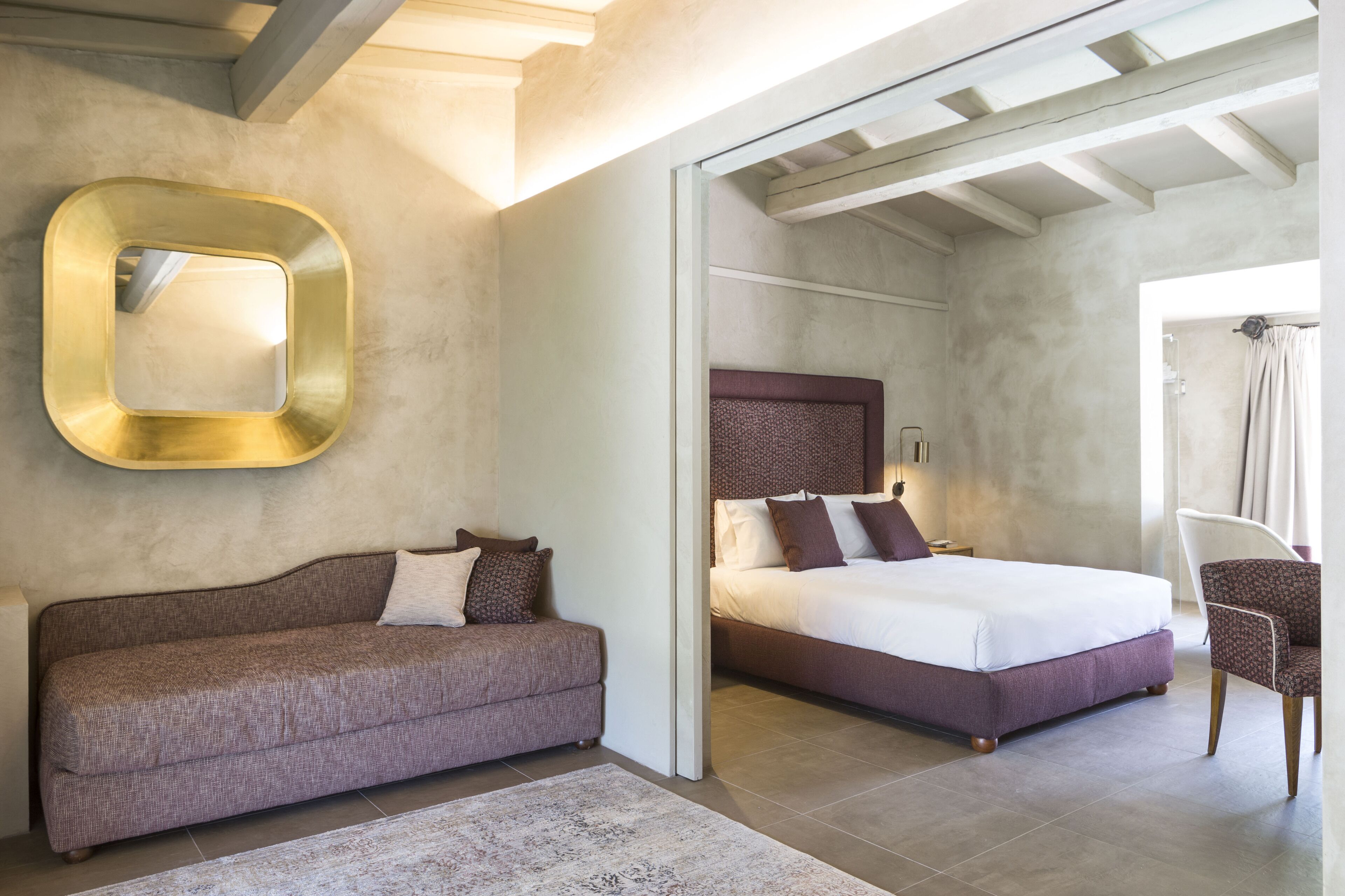 Ein modernes Hotelzimmer mit einem großen Bett, einer Couch, einem Sessel und einem Spiegel an der Wand.