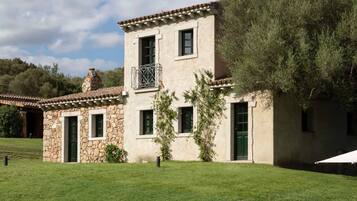 A two-story building with a stone facade, green shutters, and a tiled roof.