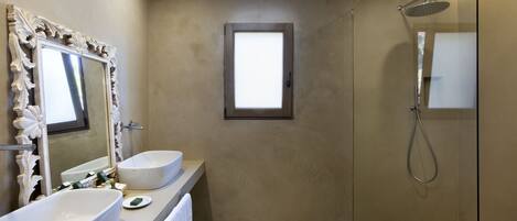 A bathroom with two sinks, a mirror, a shower, and a window.
