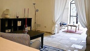 A room with a bed, a small table with a lamp, a chair, and a window with curtains. - La Vigna Vecchia (Fasano)