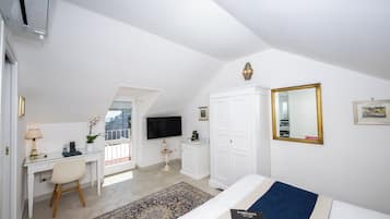 A bedroom with a bed, a desk, a chair, a TV, a wardrobe, and a window with a view.