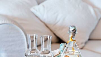 Un plateau avec une carafe et deux verres, posé sur une table, et une nappe en dentelle en dessous.