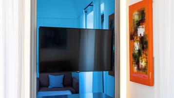 Habitación compacta con cama, televisor integrado en una pared corrediza y un mueble pequeño.