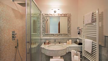 Un baño con cabina de ducha de vidrio, lavamanos de mármol, un espejo grande y un perchero para toallas.