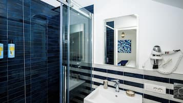 Un baño moderno con cabina de ducha de vidrio, un lavabo blanco y un espejo grande.