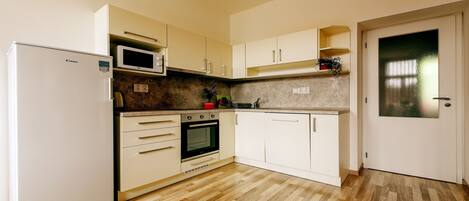 A kitchen with a refrigerator, microwave, oven, and white cabinets.