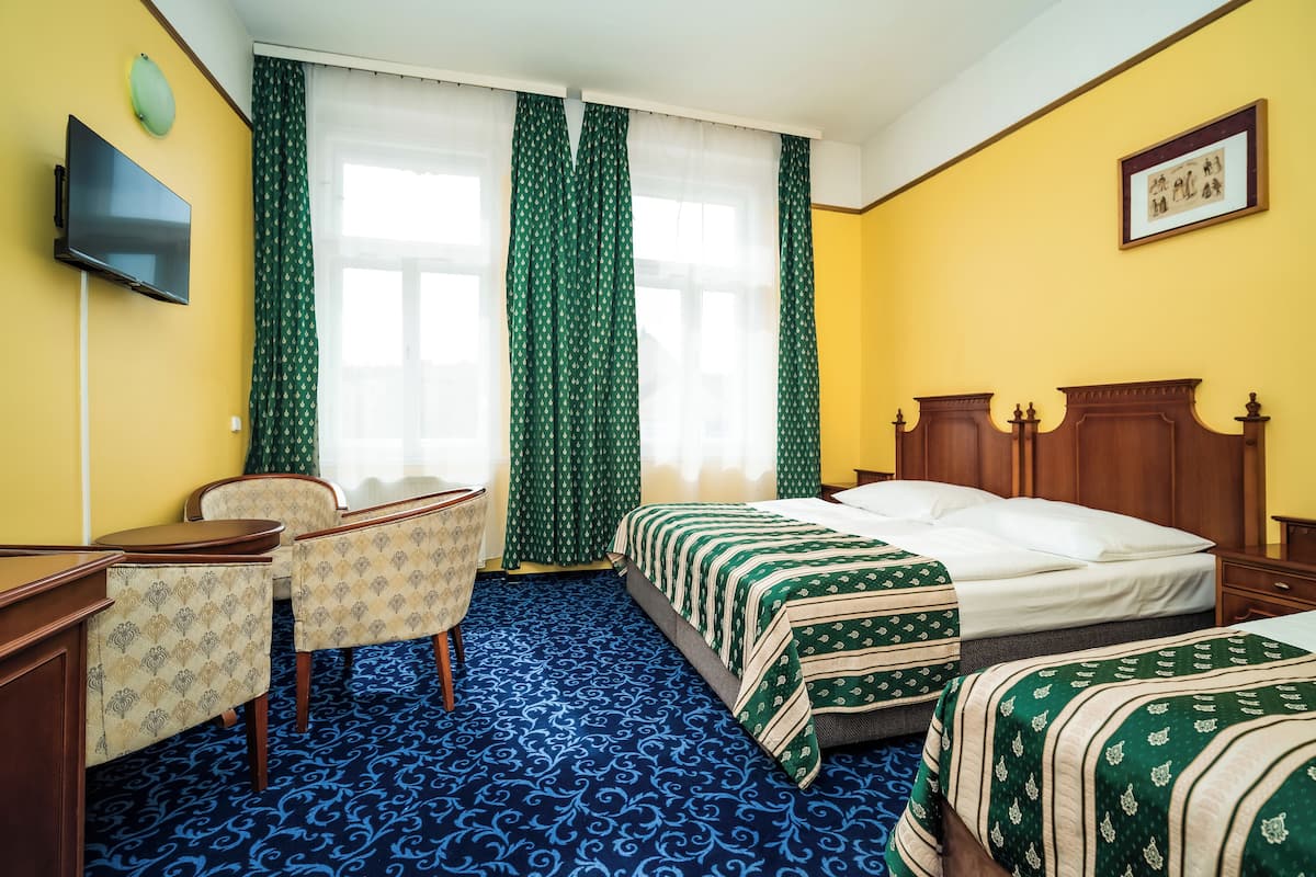 A hotel room with a bed, a desk, a chair, and a television on the wall.