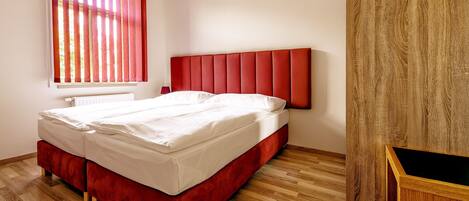 Una cama doble con cabecera roja en una habitación con suelo de madera.