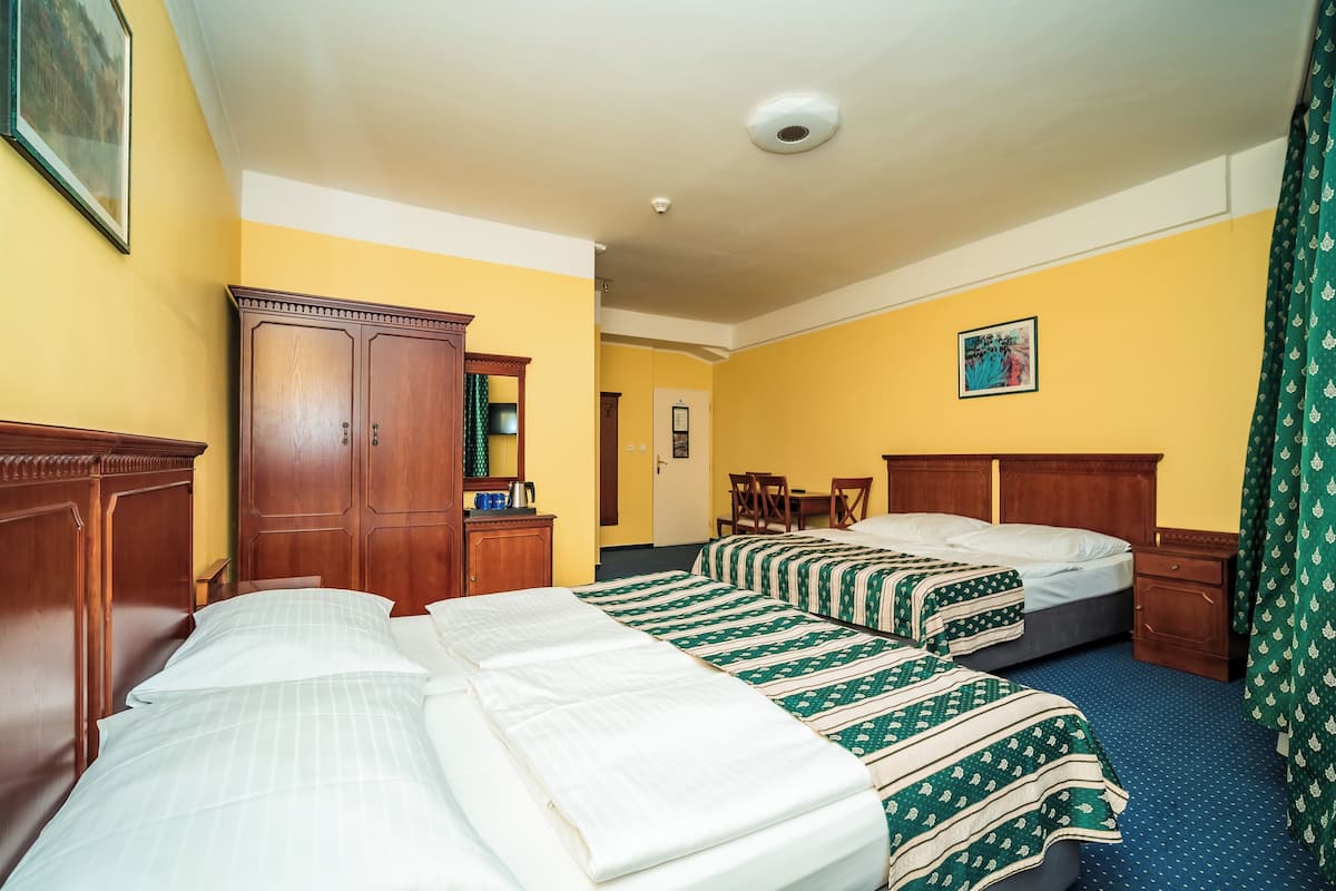 A hotel room with two beds, a wooden wardrobe, a desk, and a chair.