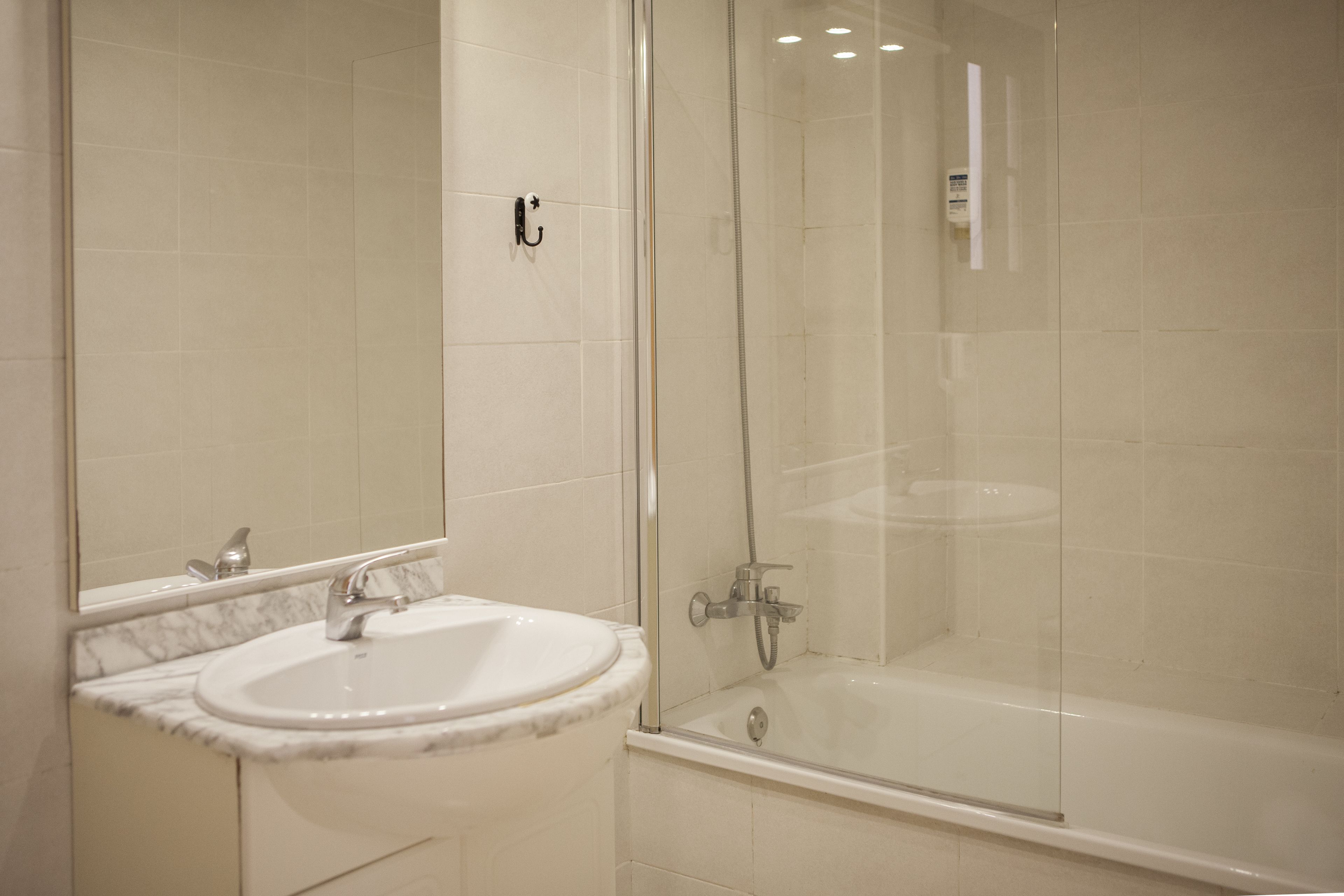 A bathroom with a sink, mirror, and glass-enclosed shower.