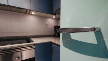 A kitchen with a stainless steel stove, a glass door refrigerator, and blue cabinets.