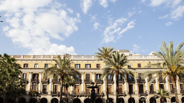 A building with a symmetrical facade, multiple balconies, and a central courtyard with palm trees. - Las Ramblas Pasaje Bacardi Apartments (Barcelona)