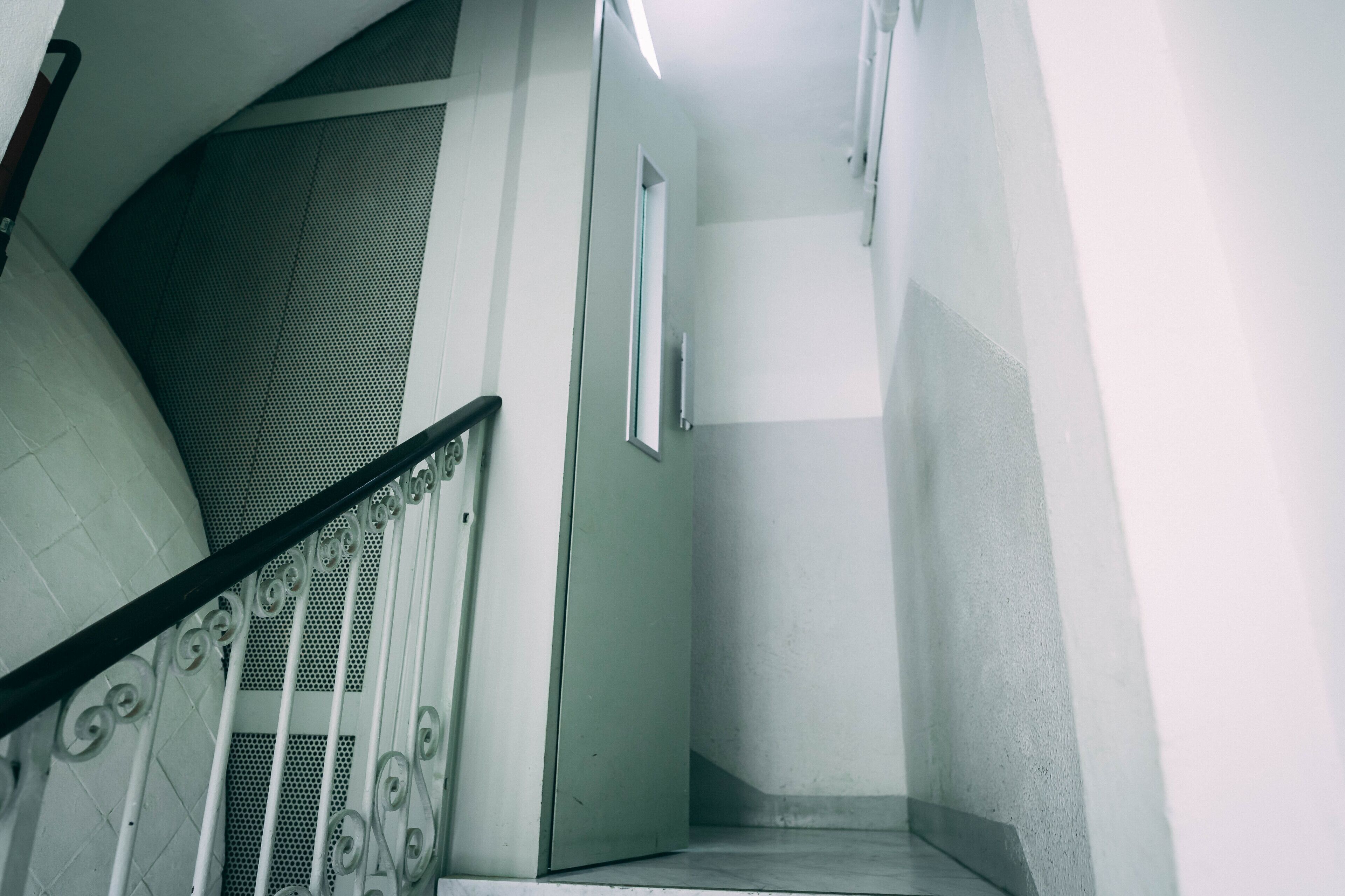 Una escalera con barandilla metálica y una puerta al final.