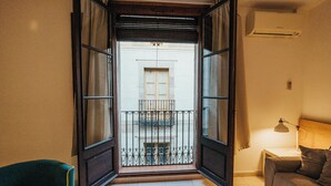An open doorway leading to a balcony with a metal railing, a small table with a lamp, and a sofa in the room. - Las Ramblas Pasaje Bacardi Apartments (Barcelona)