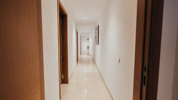 A corridor with wooden doors on one side and a white wall on the other.