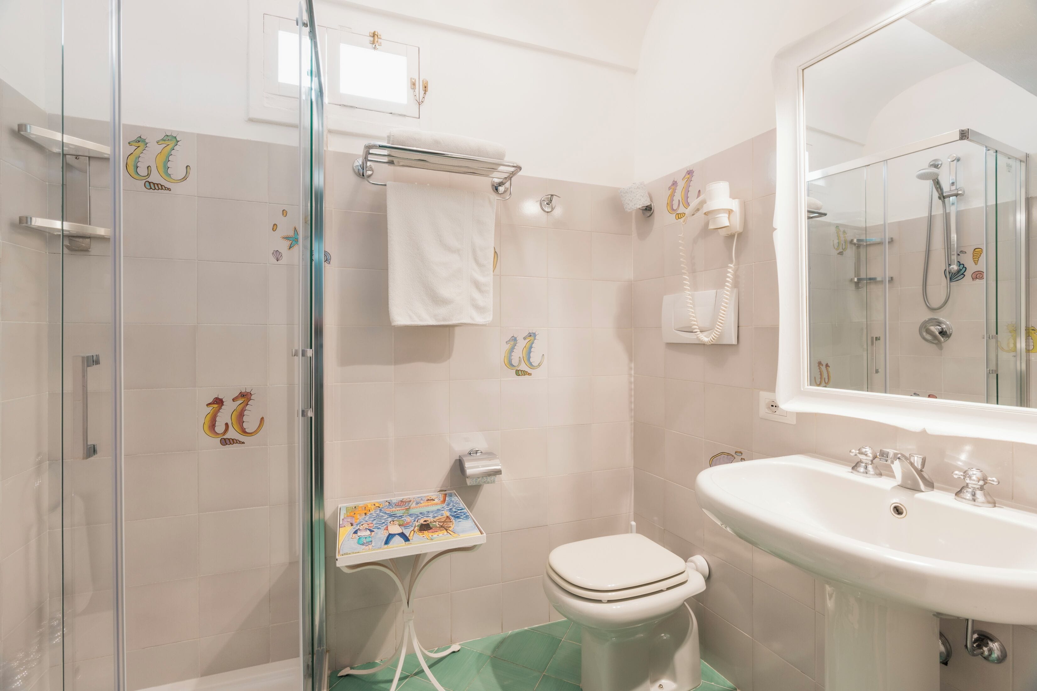A bathroom with a glass shower enclosure, a toilet, a sink, and a mirror.