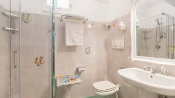 Un baño con cabina de ducha de vidrio, inodoro, lavabo y espejo.