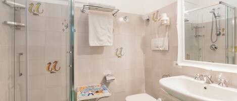 A bathroom with a glass shower enclosure, a toilet, a sink, and a mirror.