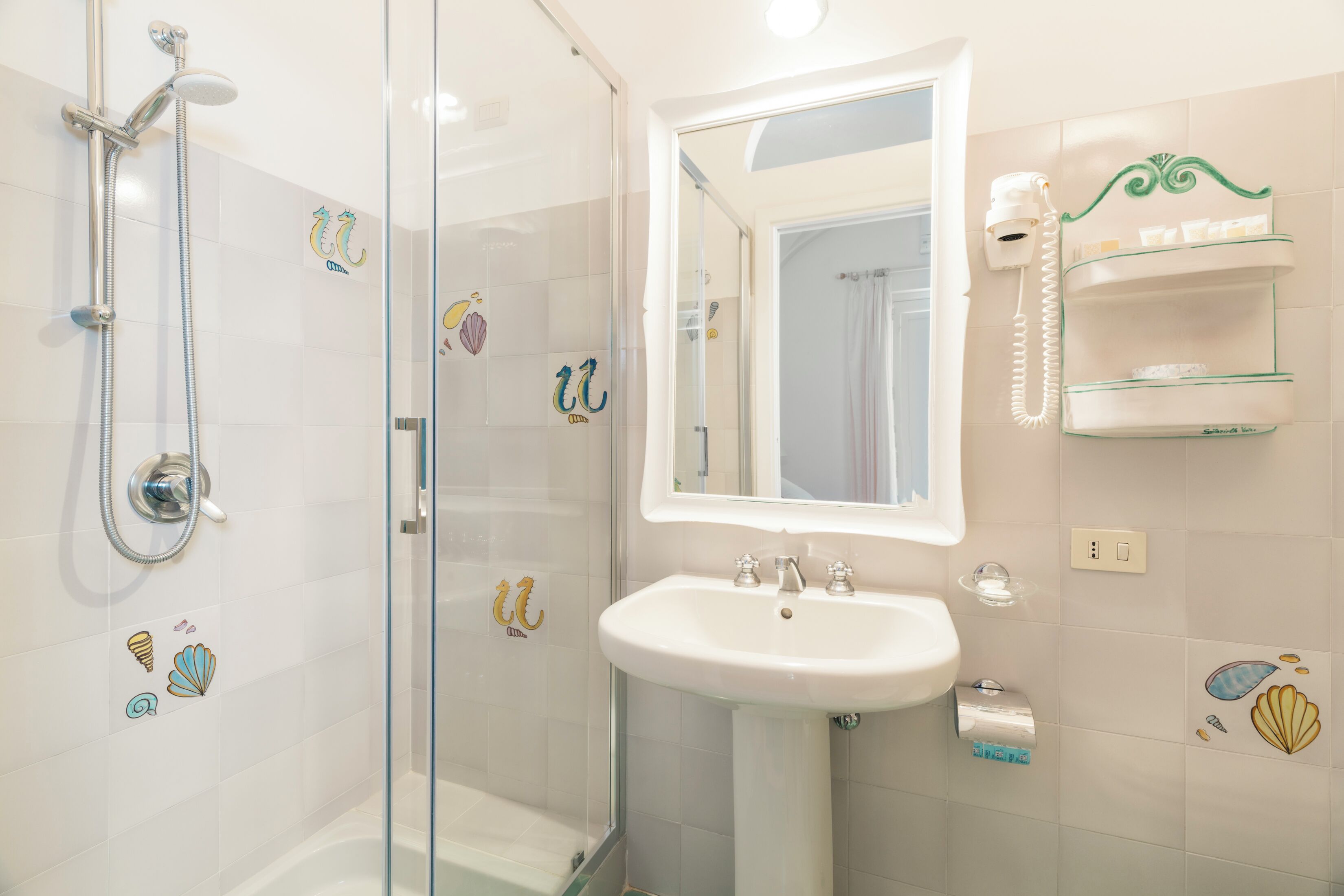 A bathroom with a glass shower enclosure, a white sink, and a mirror above it.