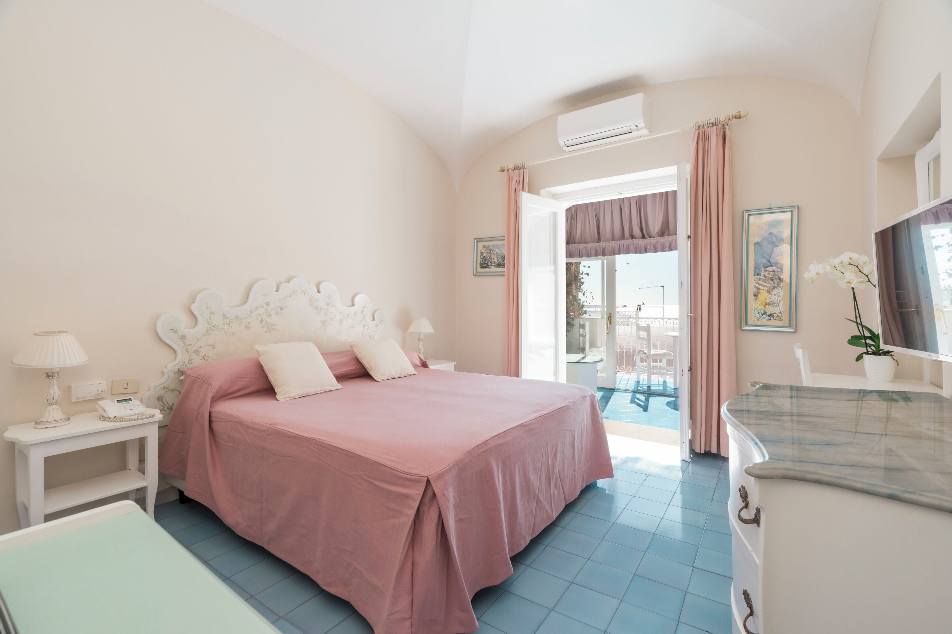 A bedroom with a bed, bedside table, and a bathroom with a sink and mirror.