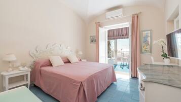 A bedroom with a bed, bedside table, and a bathroom with a sink and mirror.