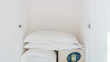 A white wardrobe with a hanging rod, a folded bed, and a small chest of drawers.