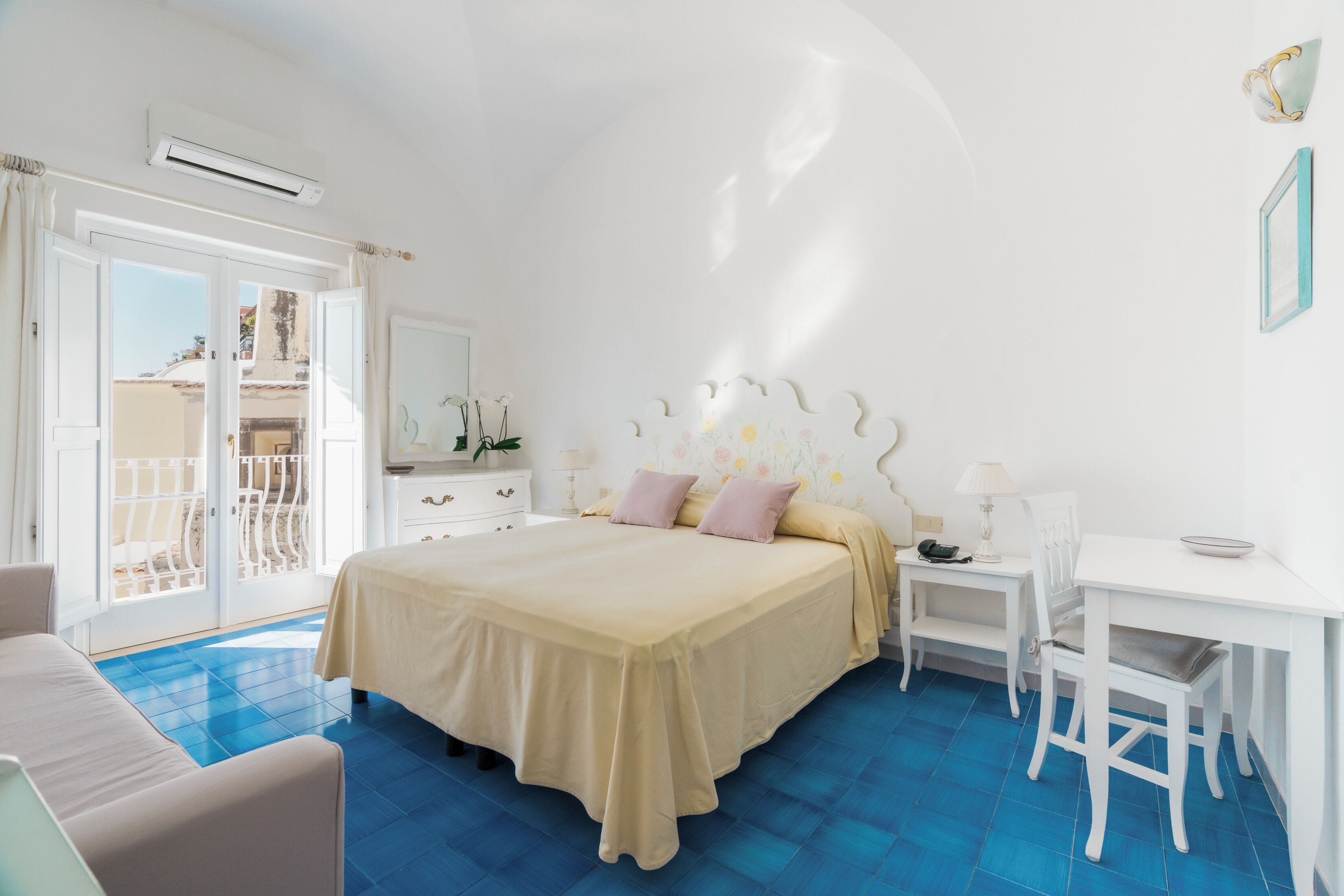 Een slaapkamer met een bed, een bureau, een stoel en een balkon.
