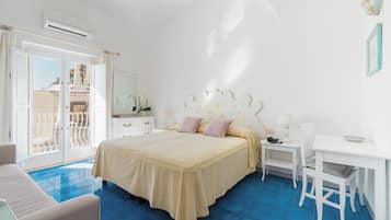 A bedroom with a bed, a desk, a chair, and a balcony.
