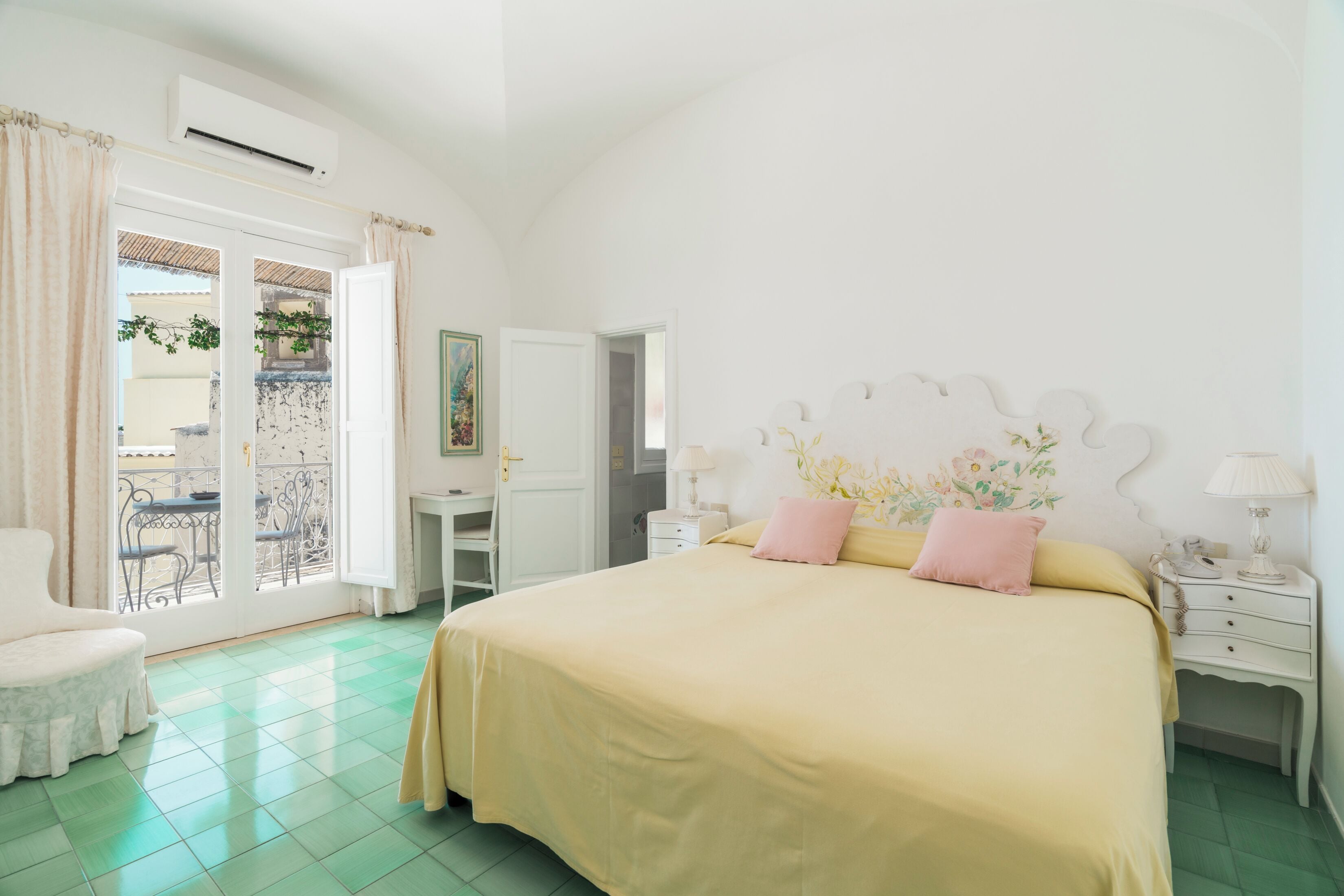 Une chambre avec un grand lit, un bureau, une chaise et un balcon équipé d’une table et de chaises.