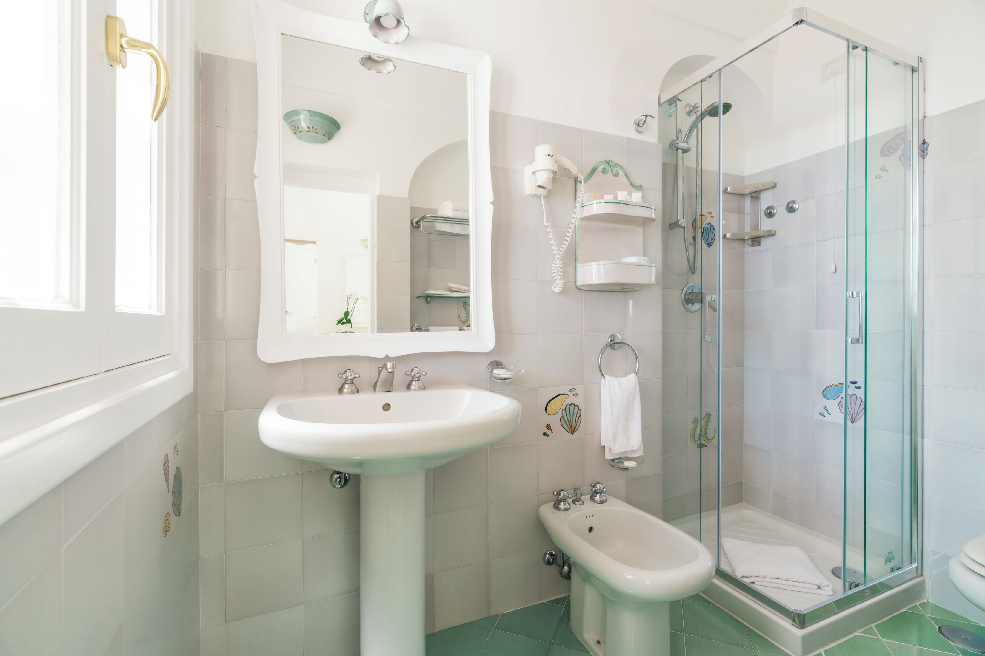 Une salle de bain équipée d’un lavabo, d’un bidet, d’une douche à parois de verre et d’un miroir.