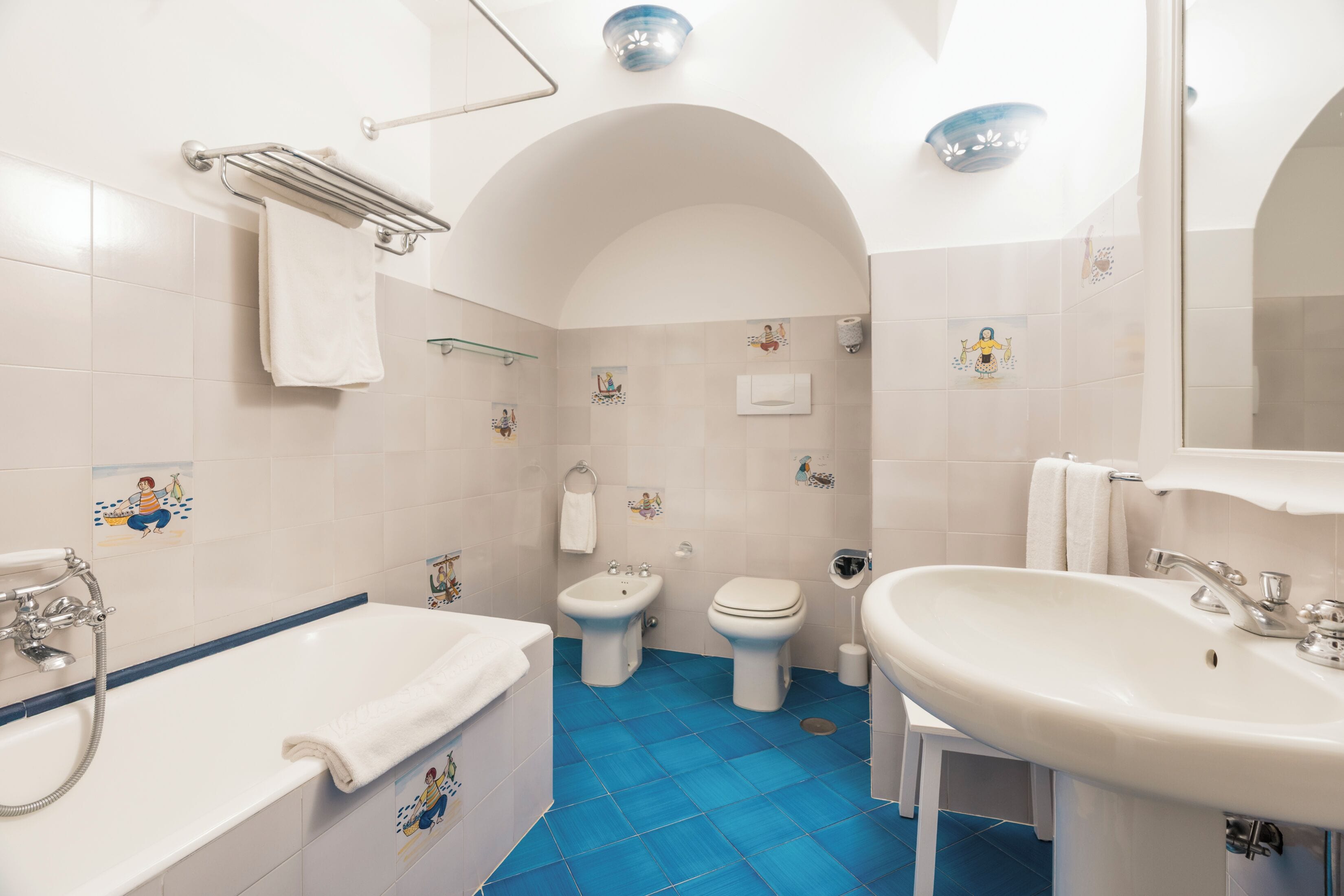 A bathroom with a bathtub, sink, and two toilets.