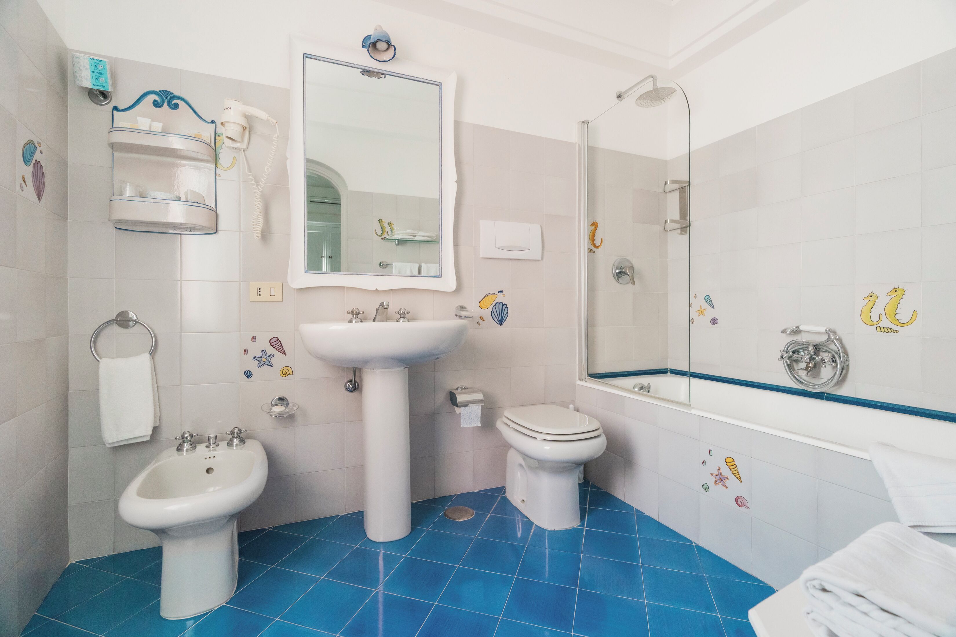 A bathroom with a sink, bidet, toilet, and shower.
