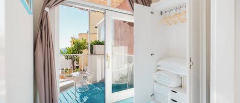 Habitació amb porta de vidre que dona a una zona de piscina, armari blanc i vista exterior.