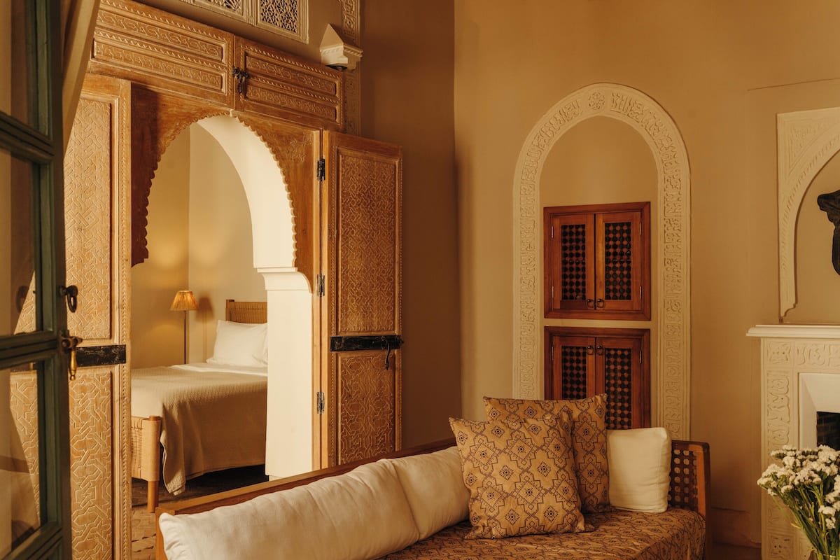 A traditional room with a bed, a sofa, and an arched doorway.