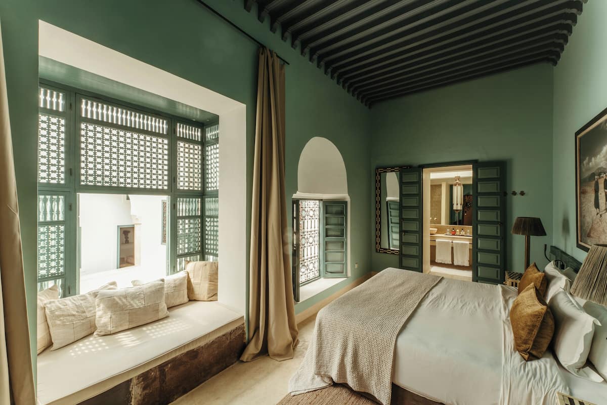 A bedroom with a large bed, a window with a view, and a door leading to a bathroom.