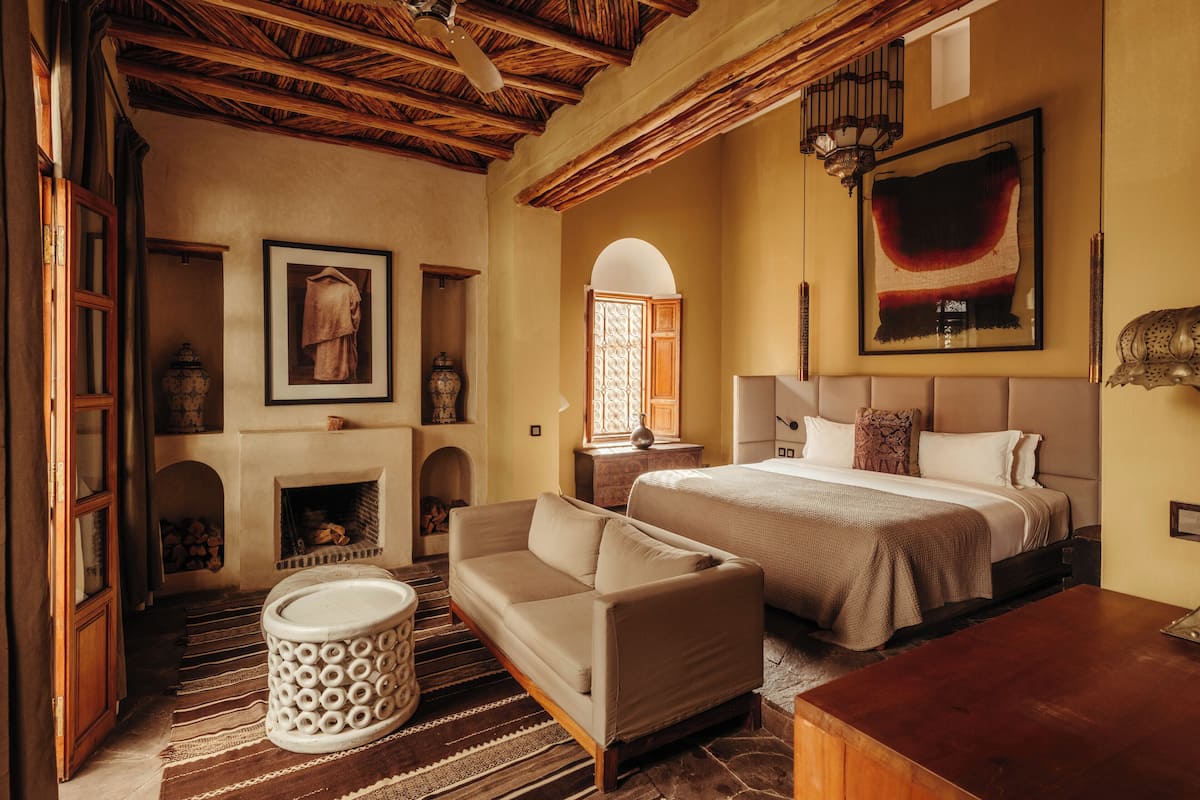 A cozy room with a bed, a sofa, a fireplace, and a large painting on the wall.