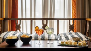 Une table à manger avec des collations, deux verres de boissons et un bol de pâtisseries.