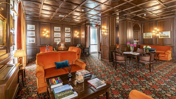 Une pièce avec un plafond en bois, une moquette à motifs floraux et des meubles orange.