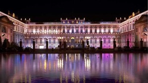 Un grand bâtiment illuminé, doté d’une façade symétrique et d’une cour intérieure qui reflète les lumières.
