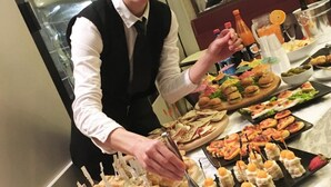 A buffet setup with various food items and a person serving. - Numi & Medusa (Cesenatico)