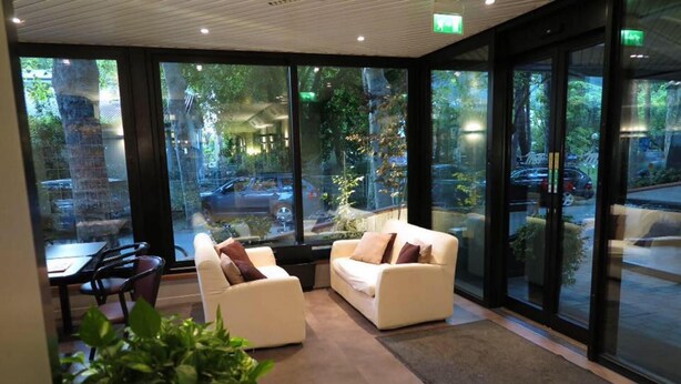 A modern interior with large windows, two white sofas, a dining table, and chairs. - Numi & Medusa (Cesenatico)