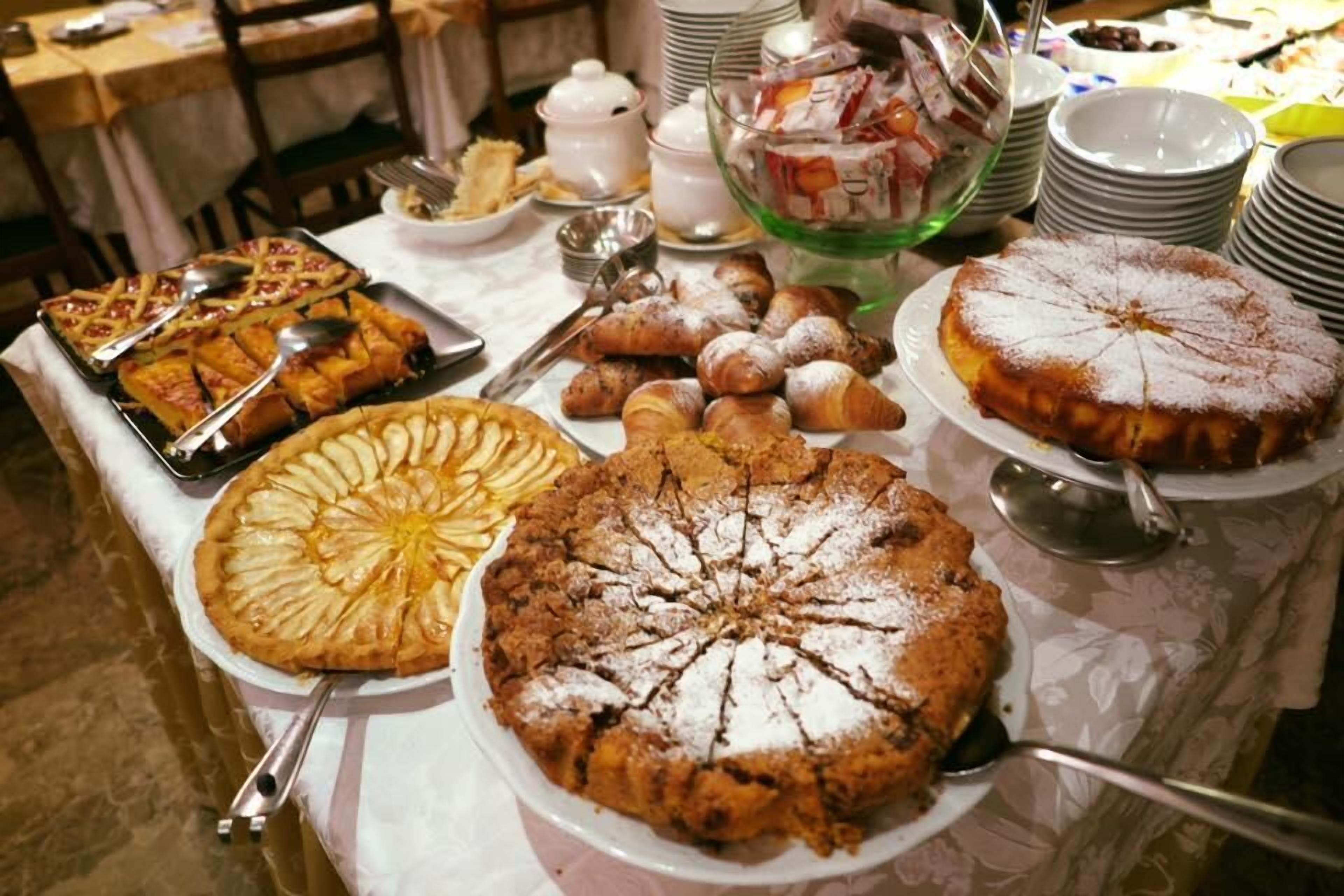 A buffet table with various desserts including pies and pastries.