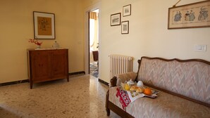 A room with a bed, a wooden cabinet, and a radiator. There are framed pictures on the wall and a door leading to another room. - B&B Camere Andrei (Pienza)