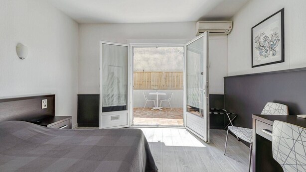 Habitación de hotel con cama, escritorio, silla y vistas al patio exterior.