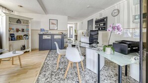 Una cocina moderna con una mesa de vidrio, sillas blancas y un ordenador portátil sobre la encimera.