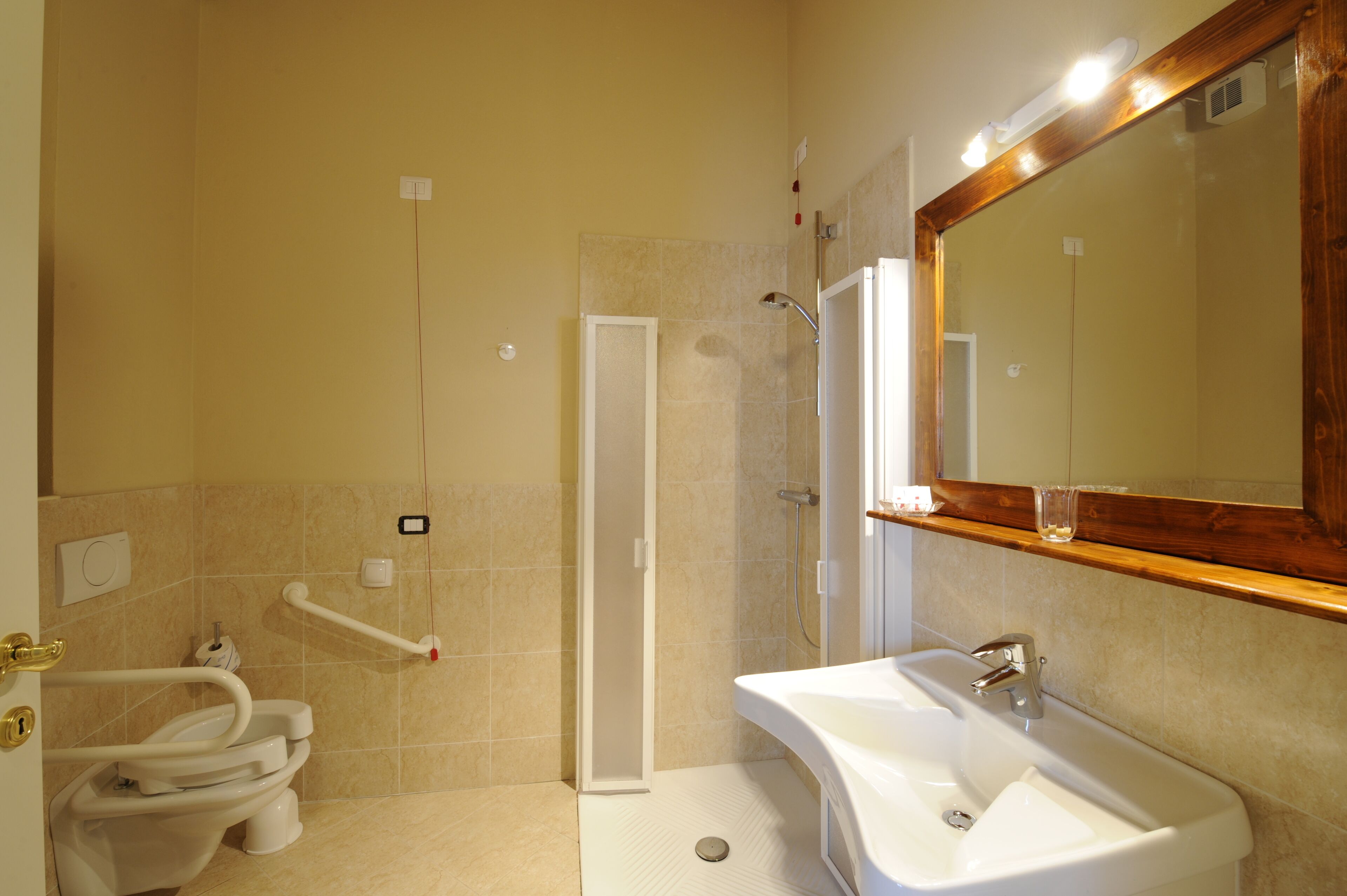Een badkamer met toilet, wastafel, douche en spiegel.