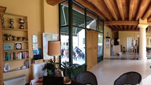 A spacious interior with high ceilings, large windows, and a central seating area with a sofa and chairs. - Relais Corte Paradiso (Peschiera del Garda)