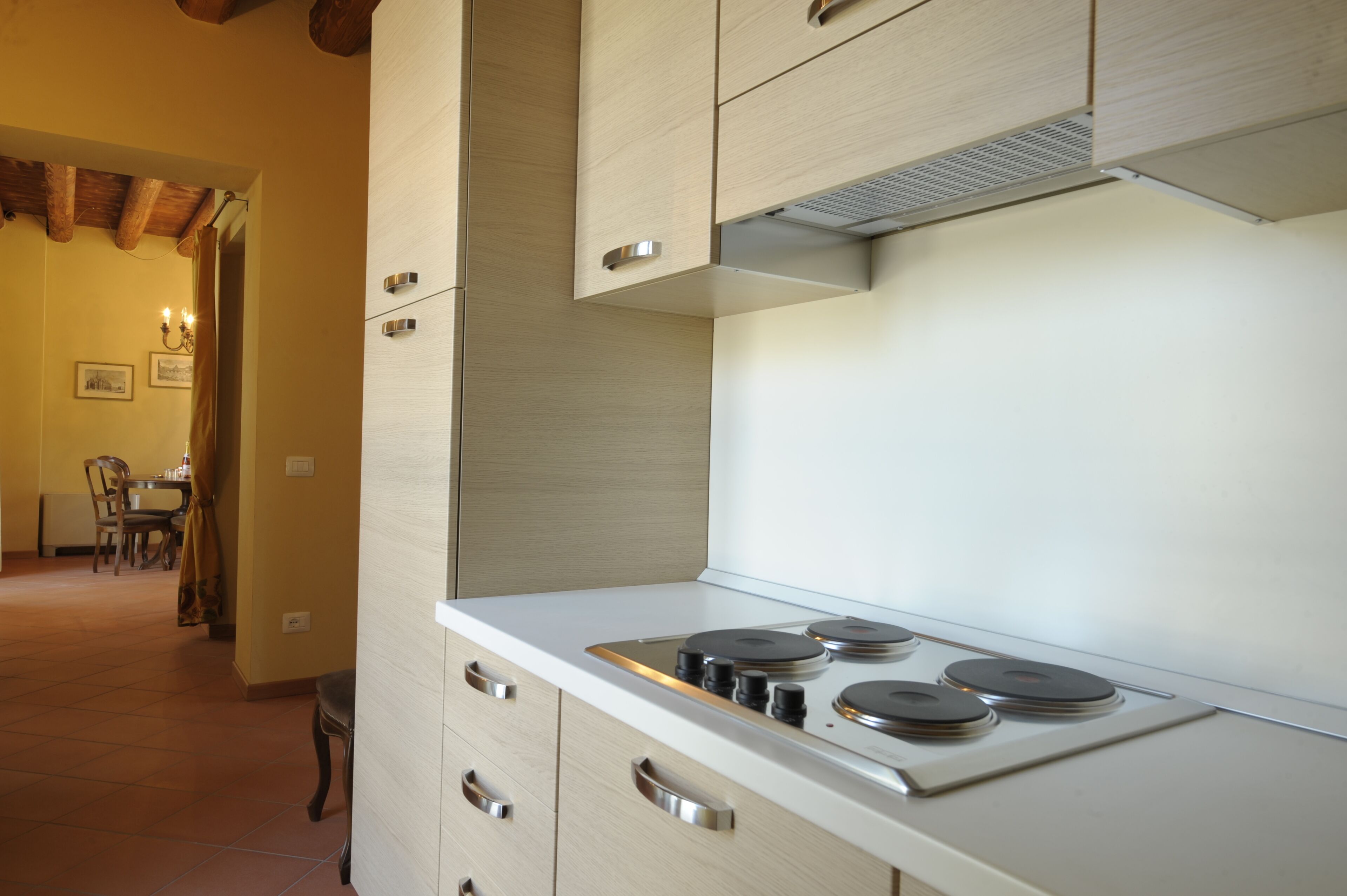 Une cuisine moderne avec un plan de travail blanc, une cuisinière en acier inoxydable et des meubles de couleur bois clair.